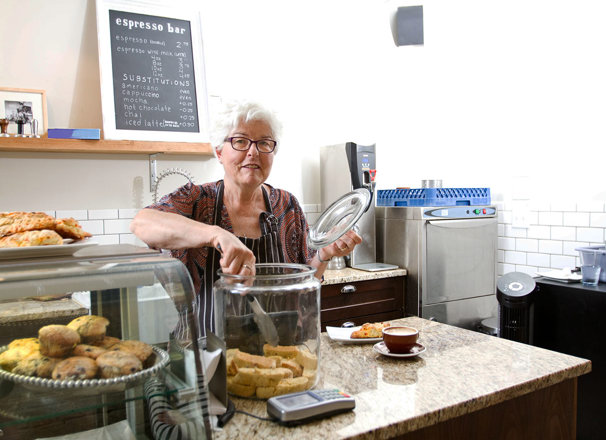 Person taking a cookie from a jar while working at a cafe