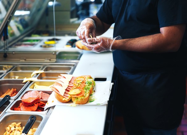 Person making a sandwich in a commercial kitchen. 