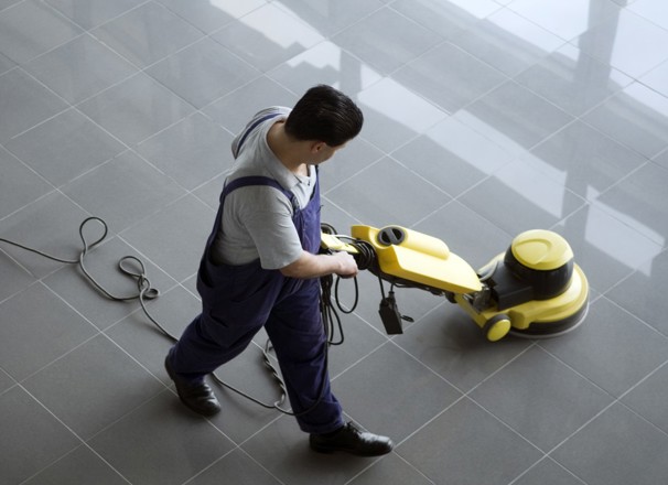 Person cleaning floor with electric floor cleaner.