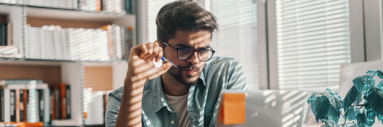 Person in thought while looking at laptop at their desk. 