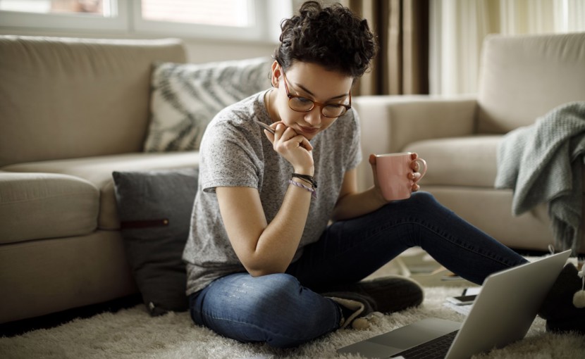 Person sitting on floor and using laptop.
