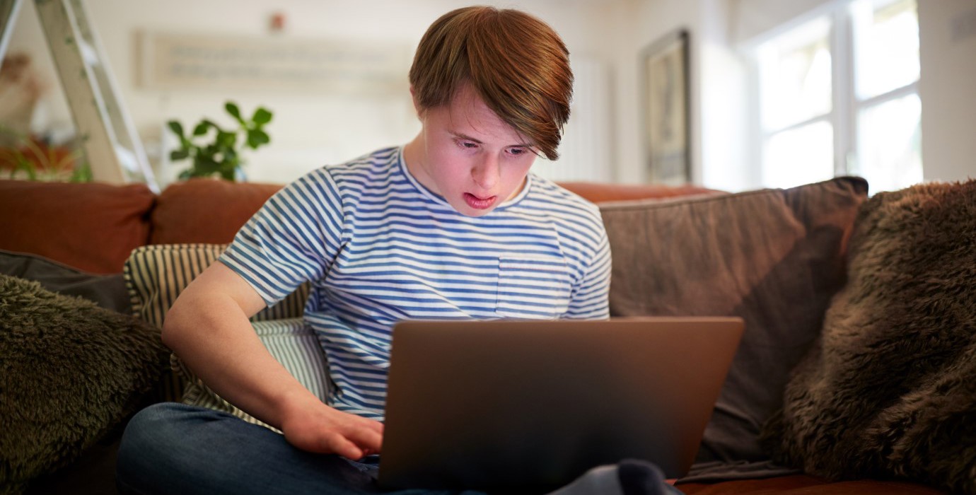 Person sitting on couch and looking at laptop.
