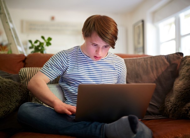 Person sitting on couch and looking at laptop. 