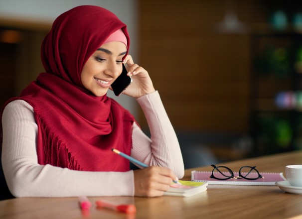 Person speaking on phone and taking notes. 