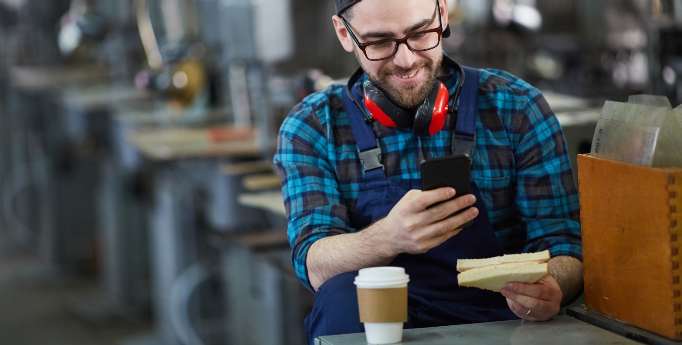 Person eating sandwich and drinking coffee on their break at a factory.