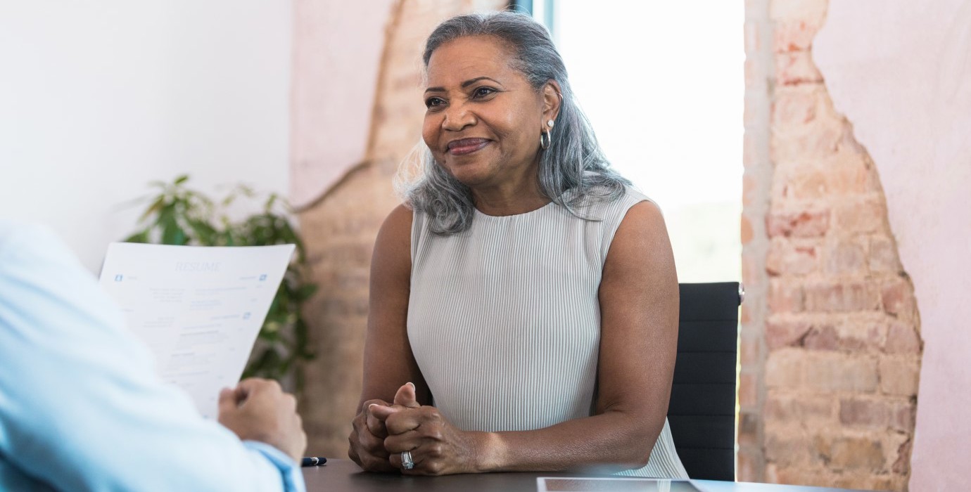 Woman waiting politely while an interviewer reviews her resumé. 