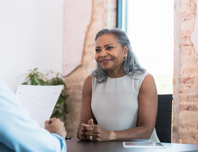 Woman waiting politely while an interviewer reviews her resumé. 