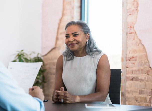 Woman waiting politely while an interviewer reviews her resumé. 