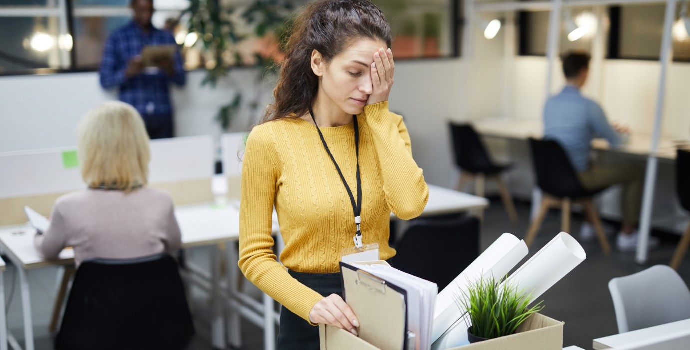 Person packing personal items in box after being fired from office job. 