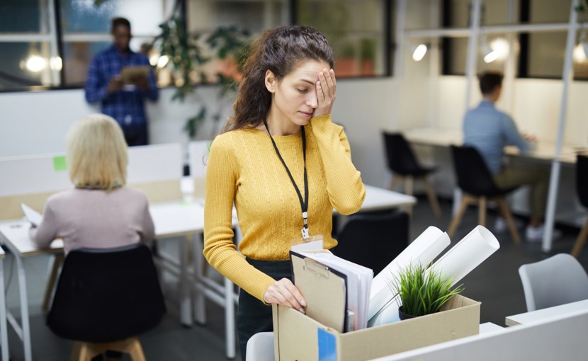 Person packing personal items in box after being fired from office job. 