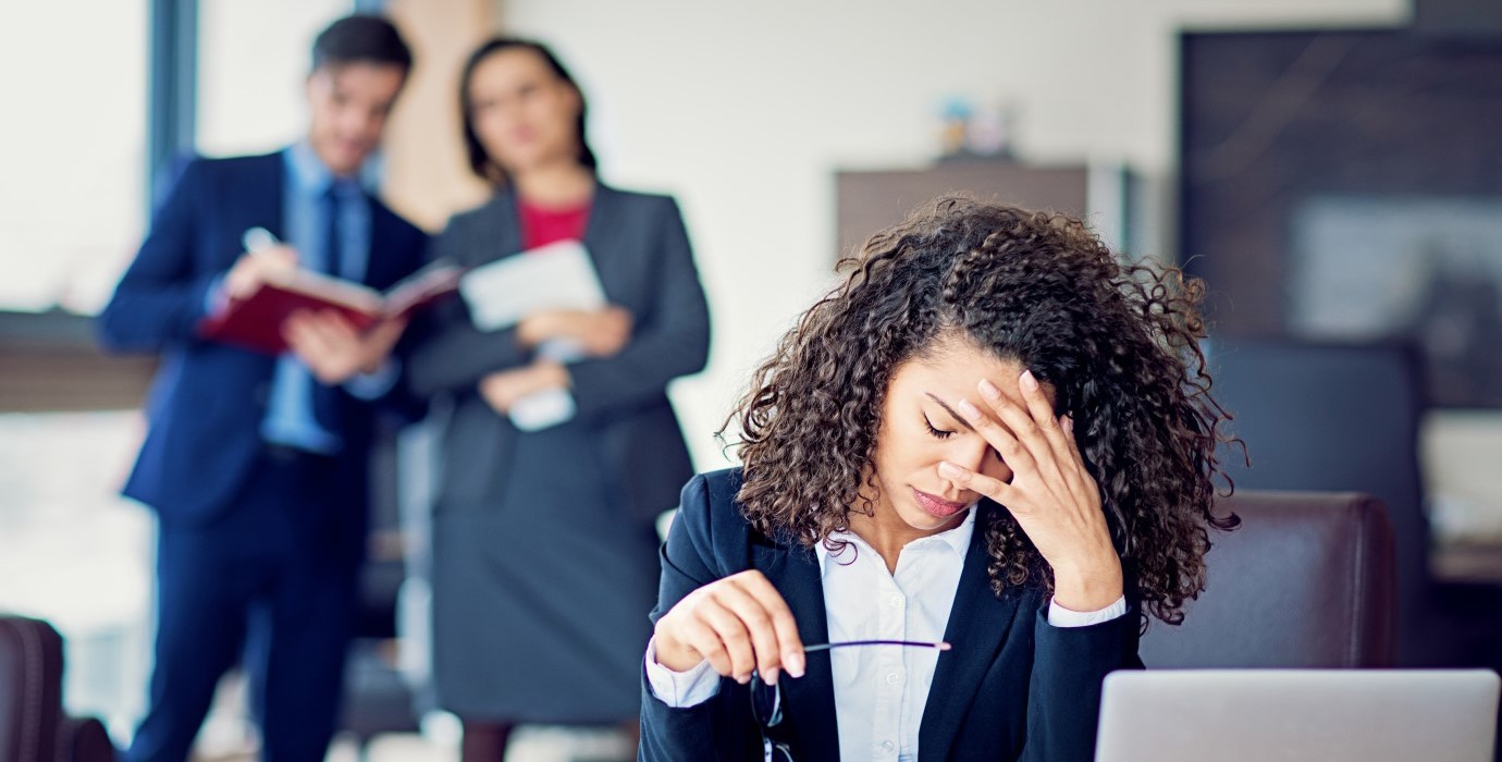 Office worker looking stressed as 2 managers watch over and take notes.
