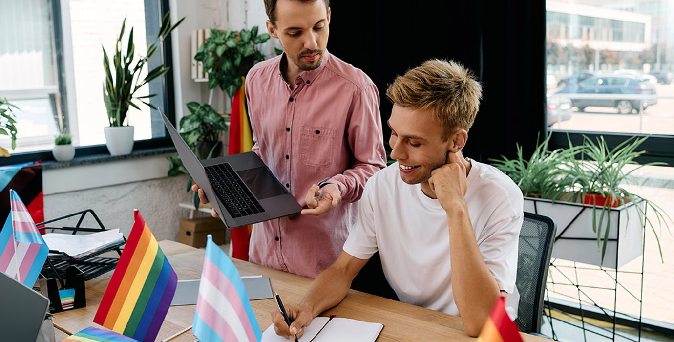 2 colleagues working at desk with transgender and pride flags