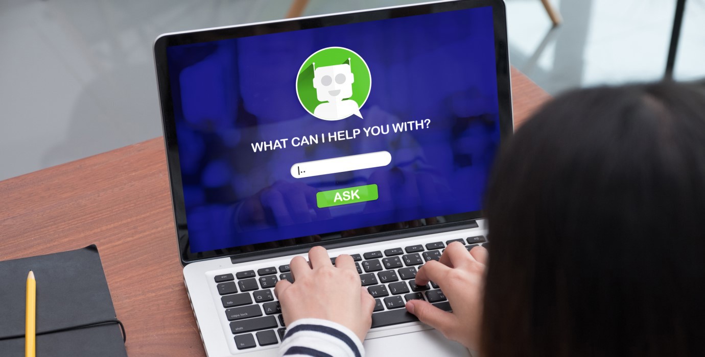 Person typing a question into a chatbot on a laptop. 