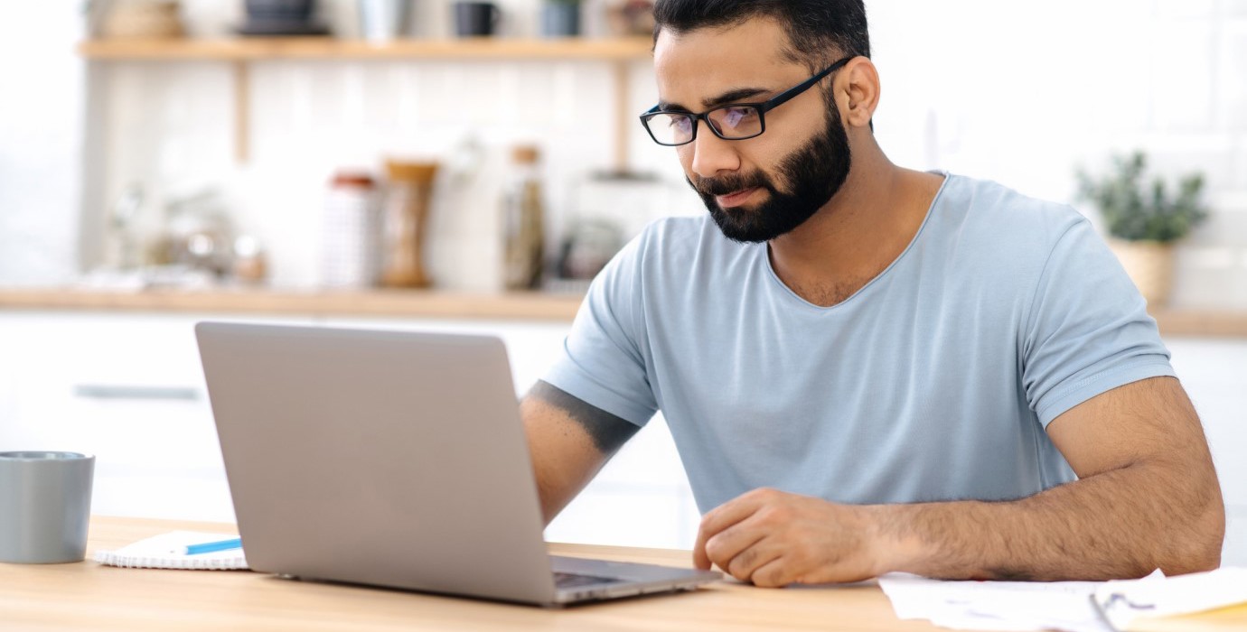 Person looking at laptop while sitting at desk. 