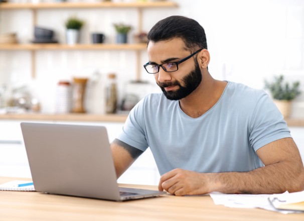 Person looking at laptop while sitting at desk. 