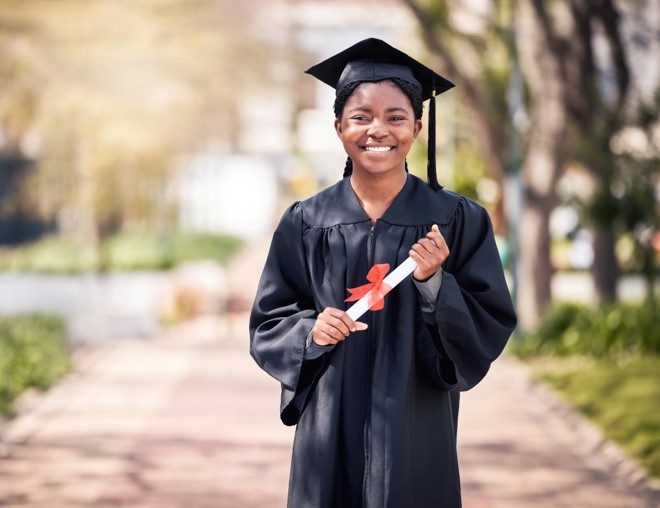 Student posing in cap and gown on high school graduation day. 