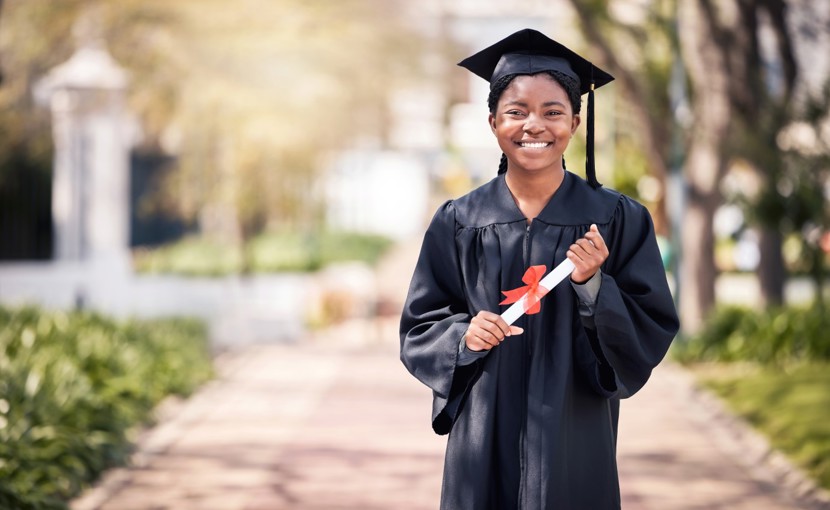 Student posing in cap and gown on high school graduation day. 